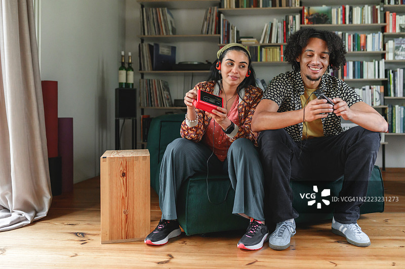 年轻的男女在沙发上用复古的随身听和卡带播放器听音乐图片素材