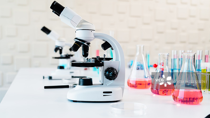 一排现代显微镜放置在大学科学教室或研究实验室的工作台上。科学教育、医学院培训或大规模临床诊断设施的概念。图片素材