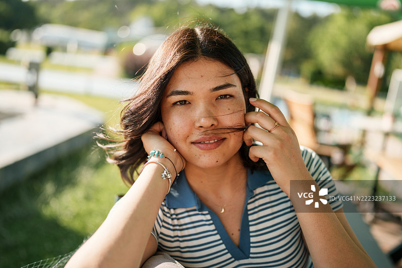 年轻女性在户外咖啡馆里看着镜头。图片素材