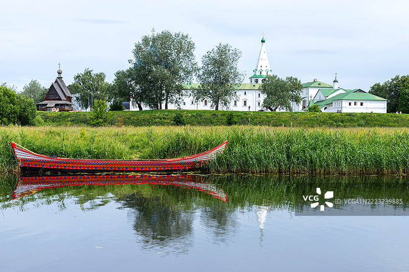 美丽的红色木船在卡门卡河上，背景是俄罗斯的苏兹达尔克里姆林宫。图片素材