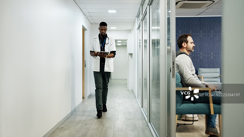 医生在医院走廊里边走边使用平板电脑图片素材