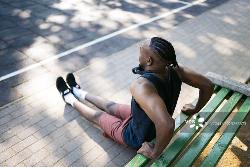 年轻男子在夏天的公园里做卧推下压。图片素材