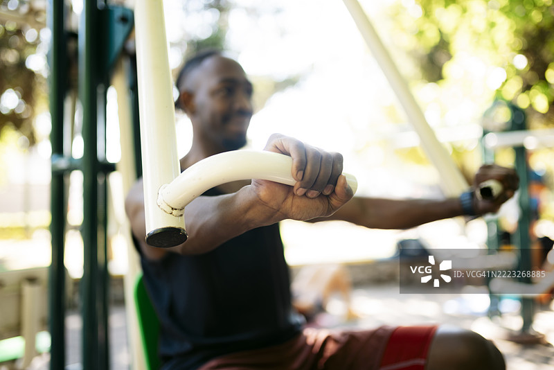 年轻男子在户外使用卧推机锻炼图片素材