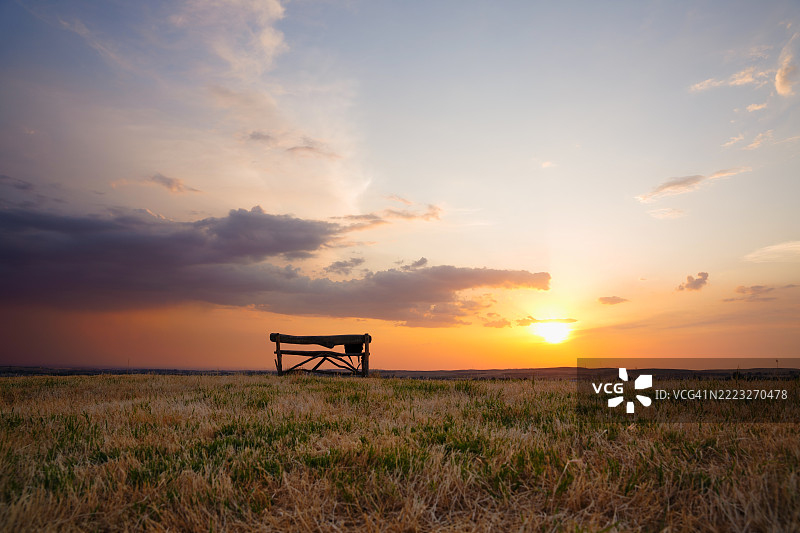 乌兹别克斯坦日落时分的空长椅在田野中图片素材
