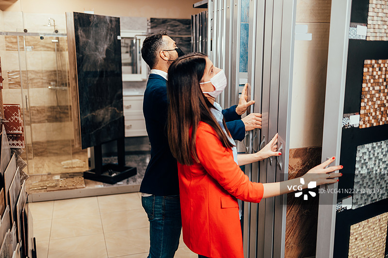 一对戴着防护口罩的情侣在浴室家具店挑选瓷砖图片素材