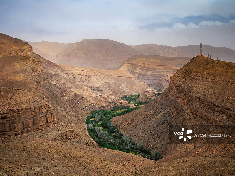 从空中俯瞰峡谷,河床上布满树木,一个小型孤立村庄以及在达德斯河谷和峡谷中的山脊,布马尔内·达德斯(Boumalne-Dadès) - 提内里夫省 - 德拉-塔菲拉勒特 - 摩洛哥。图片素材