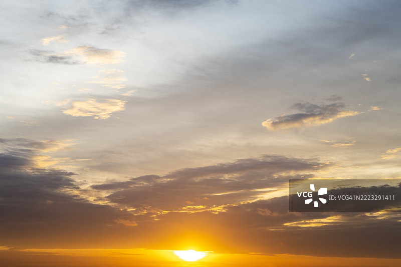 太阳在橙色和紫色的天空中落在云后图片素材