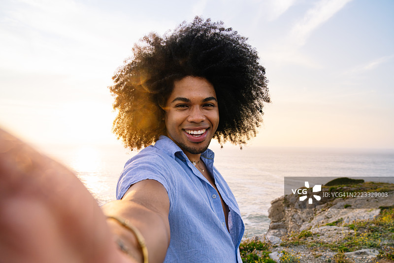 年轻人愉快地在悬崖上欣赏日落图片素材