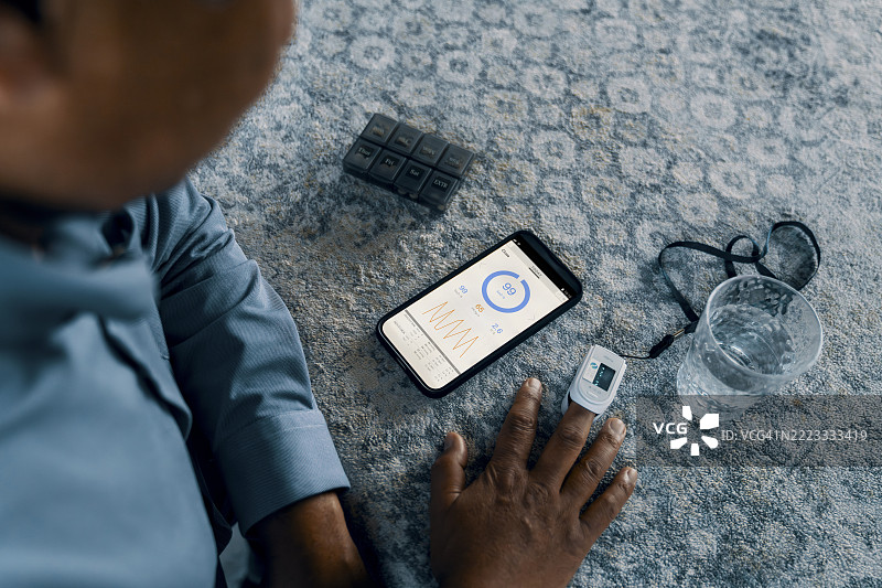 成熟男性使用医疗设备检查氧气水平，并在智能手机应用上查看数据图片素材