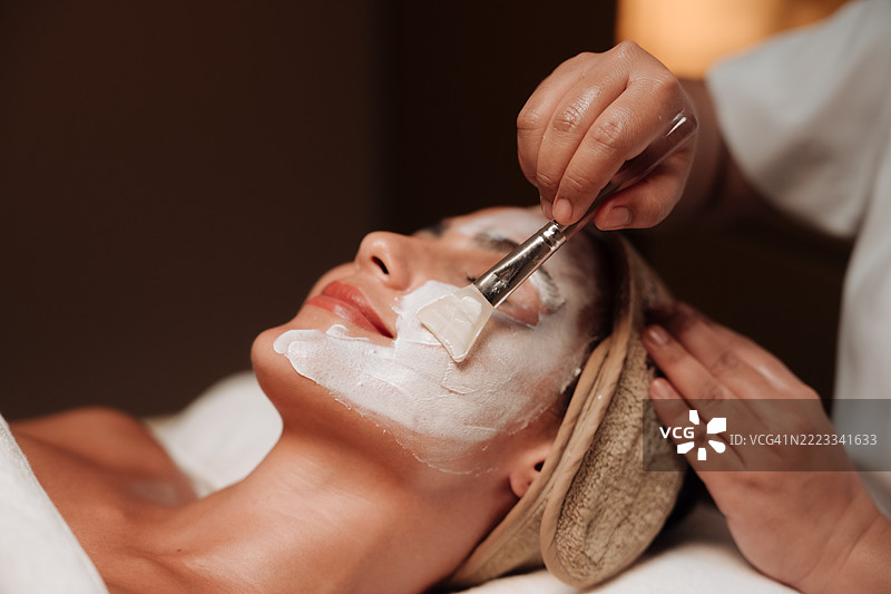 女性在健康与养生中心接受专业人士的焕肤面膜护理图片素材