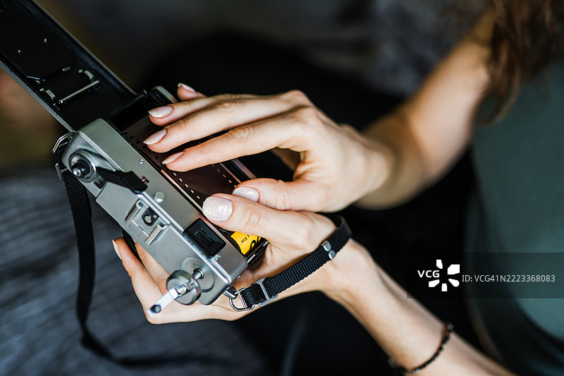 女性将胶卷装入相机以进行摄影拍摄图片素材