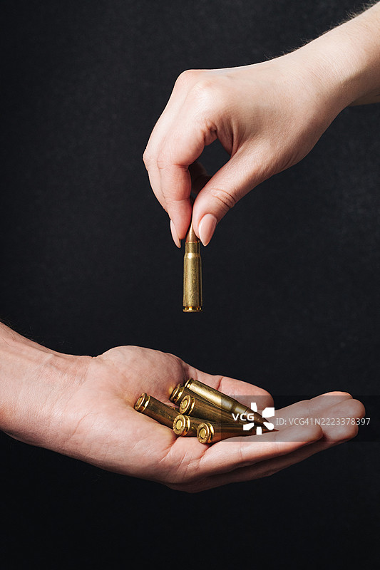 男性和女性手中拿着的7.62毫米卡拉什尼科夫突击步枪子弹图片素材