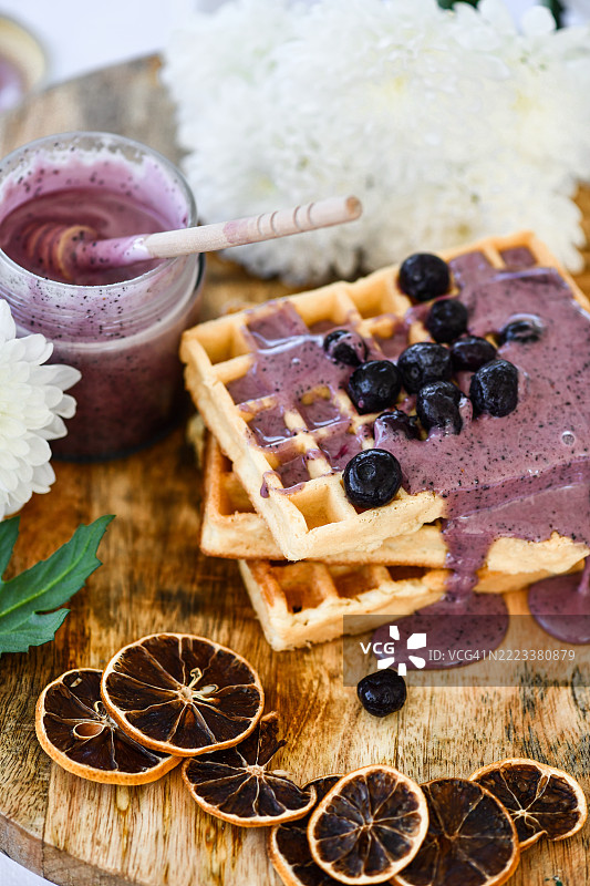 木板上放着蓝莓果酱和新鲜蓝莓的华夫饼图片素材