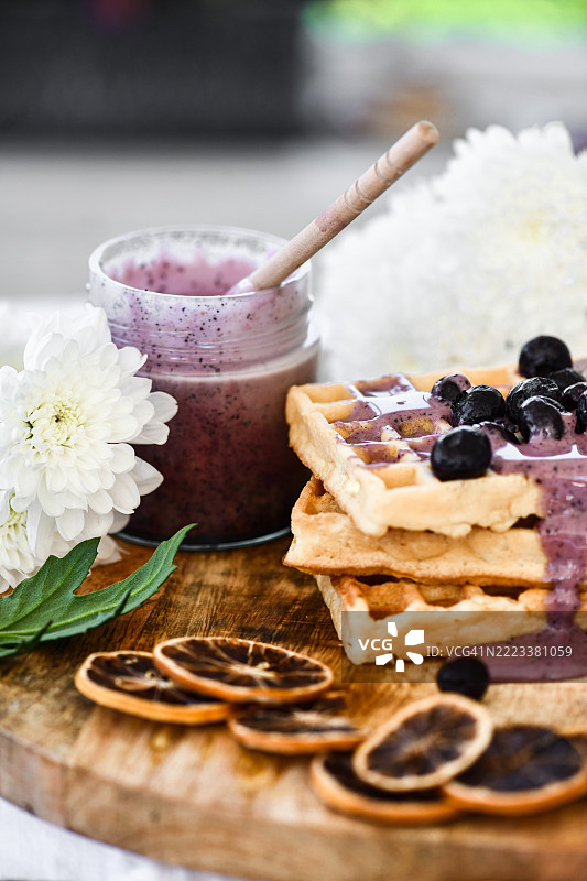 自制华夫饼配蓝莓果酱和新鲜水果，放在装饰有干橙片的乡村风格木板上图片素材