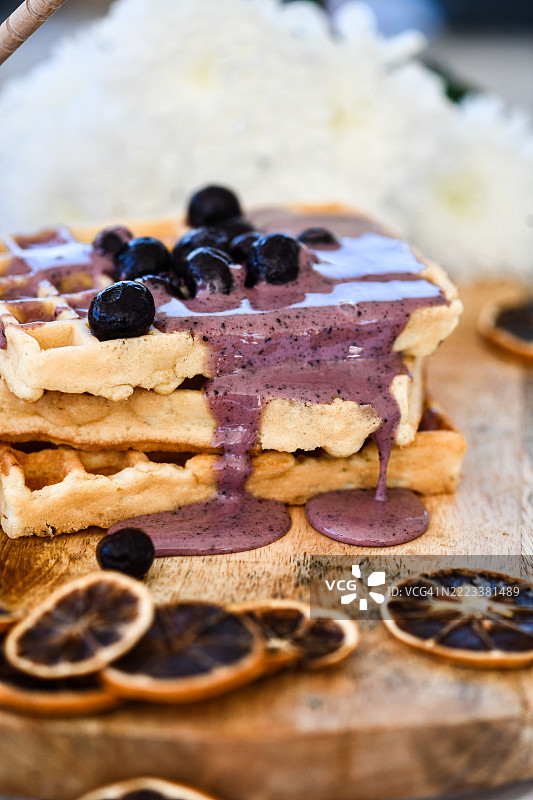 金色华夫饼配蓝莓果酱和新鲜浆果，精美地摆放在乡村风格的木板上图片素材