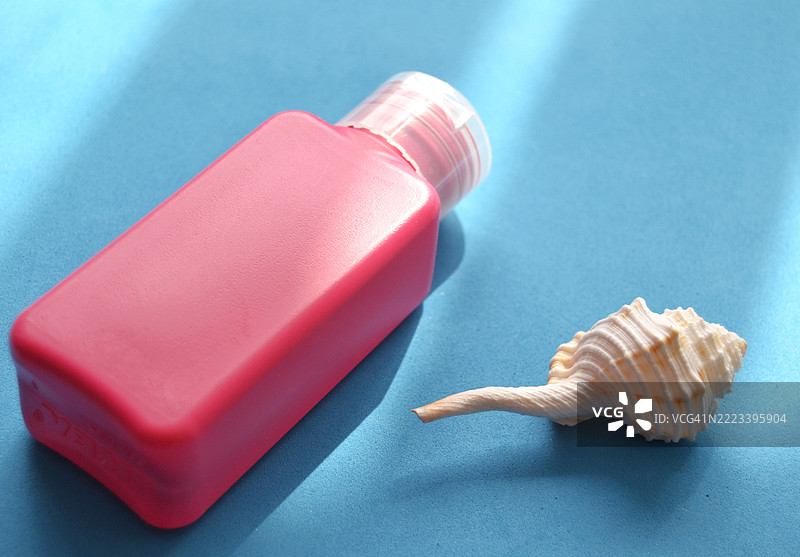 粉色塑料瓶和海螺在蓝色背景上图片素材