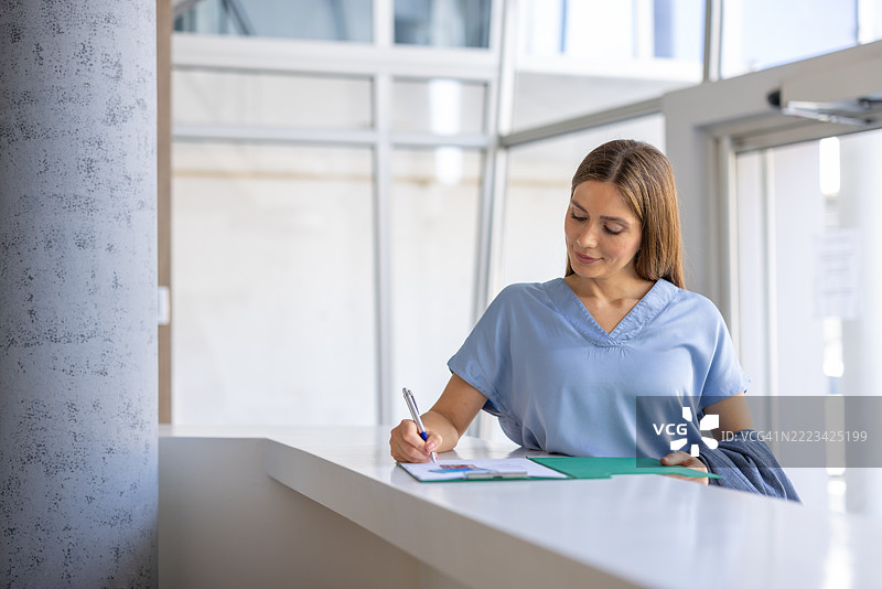 年轻女性在接待台填写文件图片素材