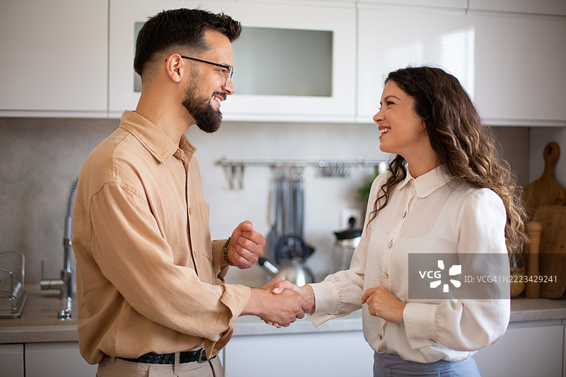 友好的同事在现代厨房握手图片素材