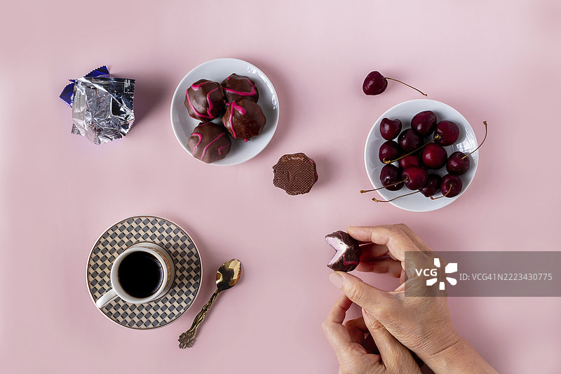 巧克力水果棉花糖、一杯咖啡、樱桃，粉色背景，选择性对焦图片素材
