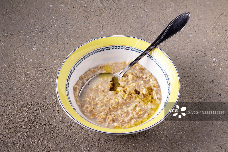 圆形陶瓷盘中的燕麦粥，淋上橄榄油，放在米色桌子上图片素材