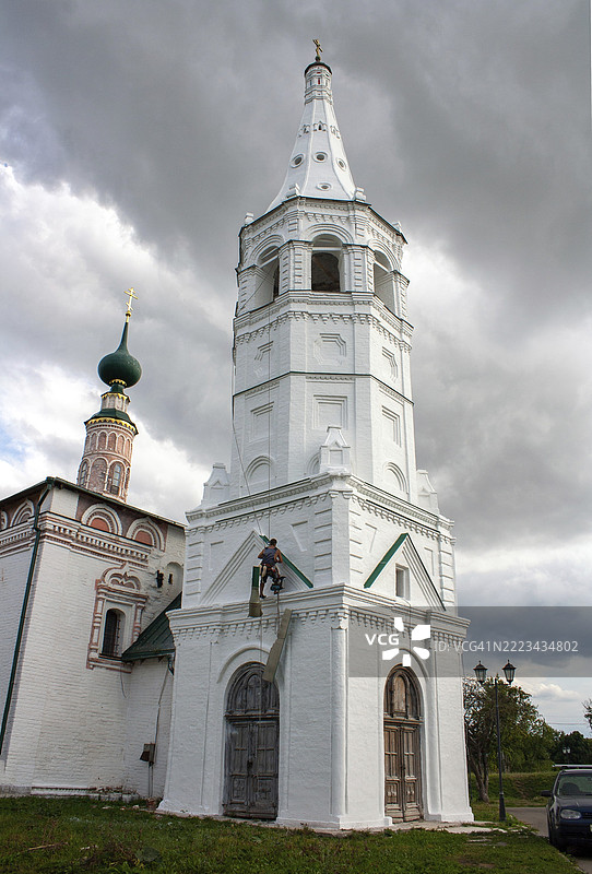 俄罗斯苏达尔 - 2022年8月7日。一名建筑工人攀登者正在修复古老俄罗斯城市苏达尔的钟楼外立面。图片素材