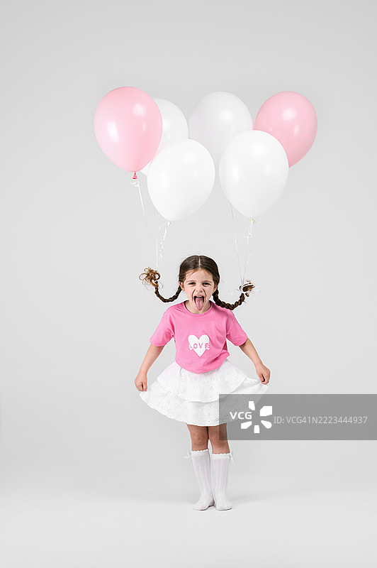 快乐的小女孩在白色背景上玩气球图片素材