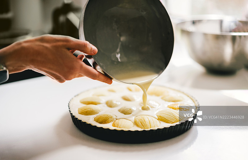在台面上的烤盘中将面糊倒在水果甜点上图片素材