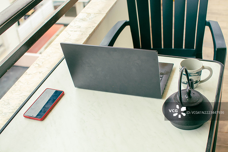 在阳台上用笔记本电脑、智能手机和茶工作图片素材