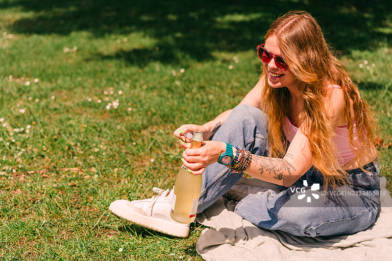 女人在户外享受野餐，手中拿着气泡饮料图片素材