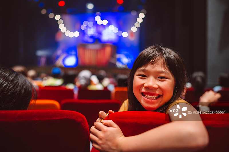兴奋的小女孩在剧院享受家庭日。图片素材