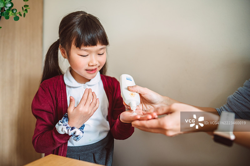 亚洲女学生在上学前涂抹防晒霜以保护皮肤免受阳光伤害图片素材