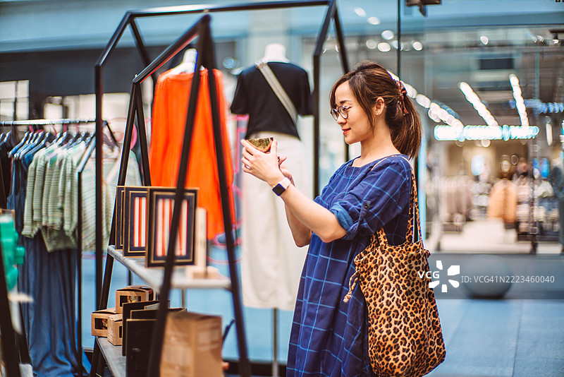 亚洲女性在时尚精品店中精心购物图片素材