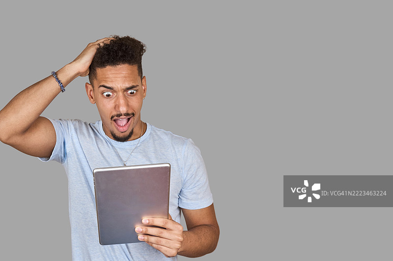 震惊的年轻人正在阅读数字平板上的意外新闻图片素材