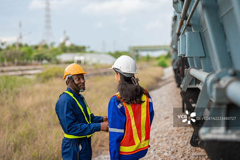 在铁路车间，维修工程师们正在讨论列车维修工作。图片素材