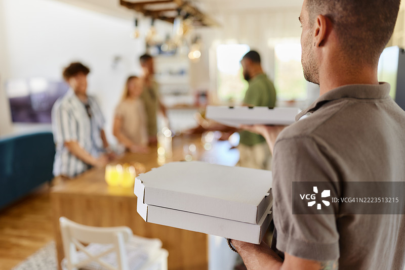 无忧无虑的男人为朋友们送披萨，参加社交聚会。图片素材