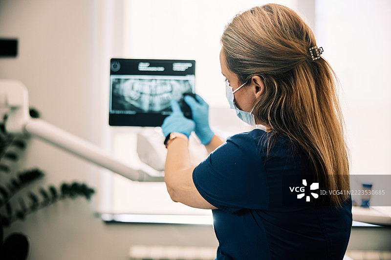 女牙医在诊所检查牙科X光片图片素材
