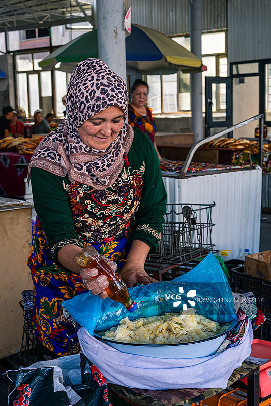 吉尔吉斯斯坦奥什；2025年7月4日。在奥什集市上出售腌制卷心菜的女性图片素材