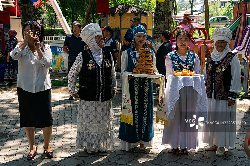 吉尔吉斯斯坦女性在奥什的阿里舍尔·纳沃伊雕像揭幕仪式上手持传统面包图片素材