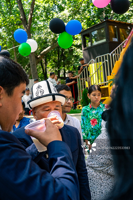 奥什市市长热尼什别克·托克托尔巴耶夫在吉尔吉斯斯坦的奥什市庆祝活动中佩戴传统的吉尔吉斯帽子饮酒。图片素材