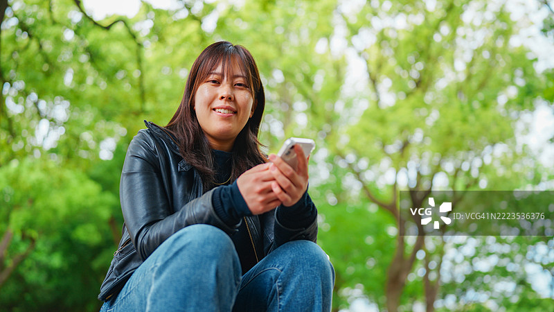 在公园里使用手机的女性肖像图片素材