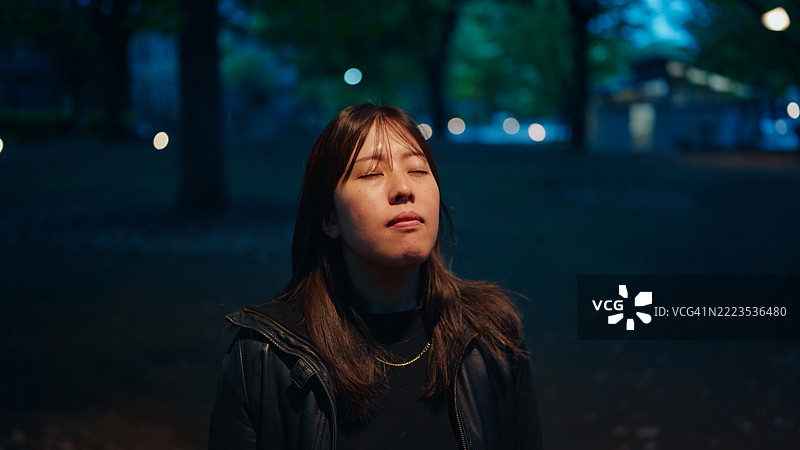 傍晚时分，女人独自在公园里站着图片素材