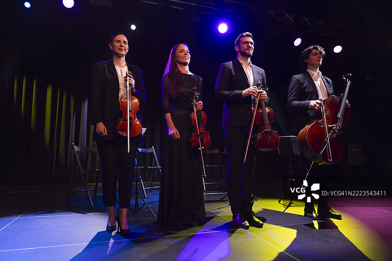 弦乐四重奏在剧院舞台上手持乐器站立。图片素材
