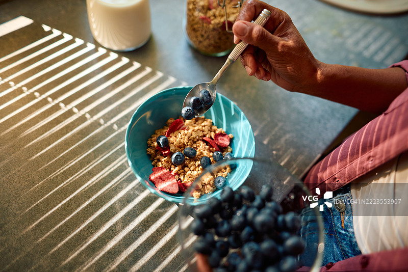 女人在早餐碗中加入蓝莓和干草莓的格兰诺拉麦片图片素材