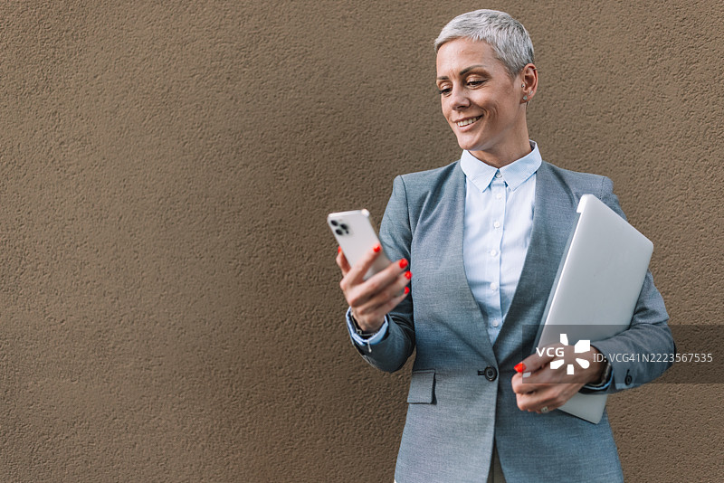 女商人同时握着笔记本电脑和智能手机图片素材