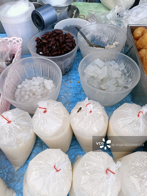 各种甜蜜的食材在桌上的塑料容器中展示，营造出诱人的场景，唤起美味甜点的感觉，泰国图片素材