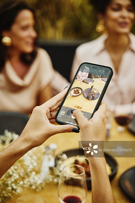 中近景拍摄用手机在晚餐时拍摄食物的手图片素材