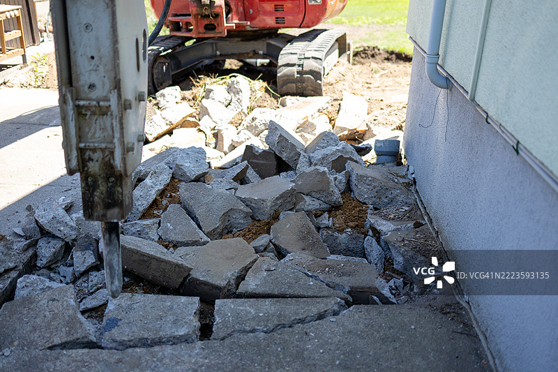 液压破碎机在建筑或拆除项目中拆除混凝土路面特写。周围工作区域散落着碎片。图片素材