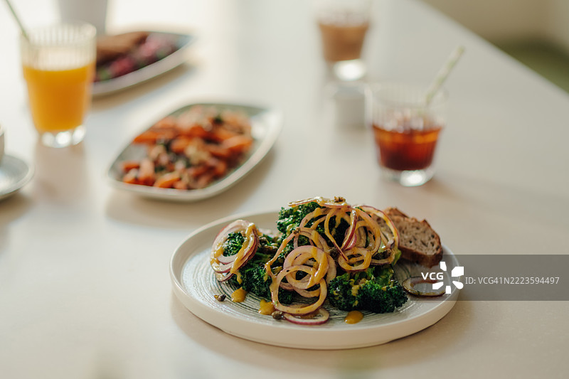 美味的西兰花沙拉，配有芥末酱和切片洋葱，摆放在白色桌子上图片素材