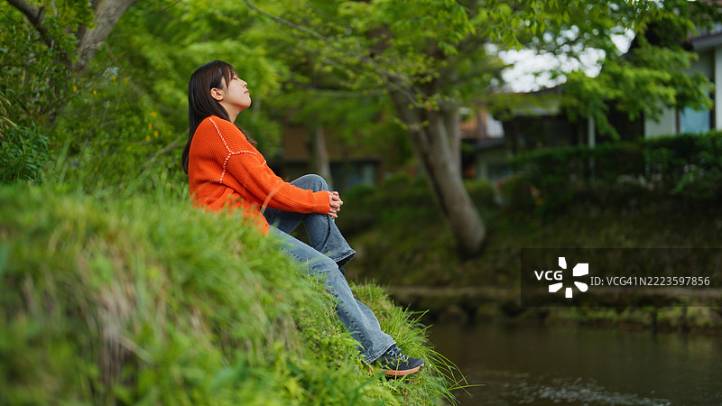 坐在大自然中，面朝上，闭着眼睛的女性肖像图片素材