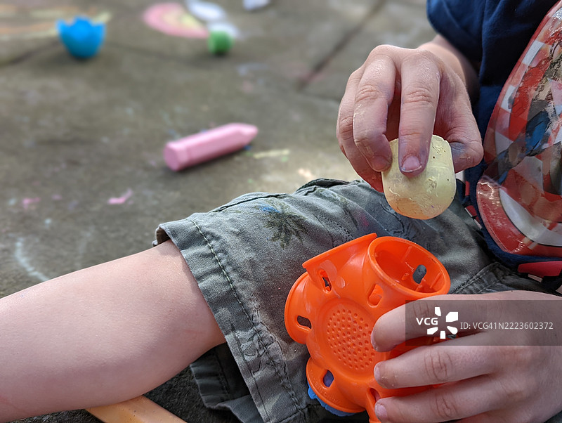 小男孩在玩人行道粉笔的特写镜头图片素材